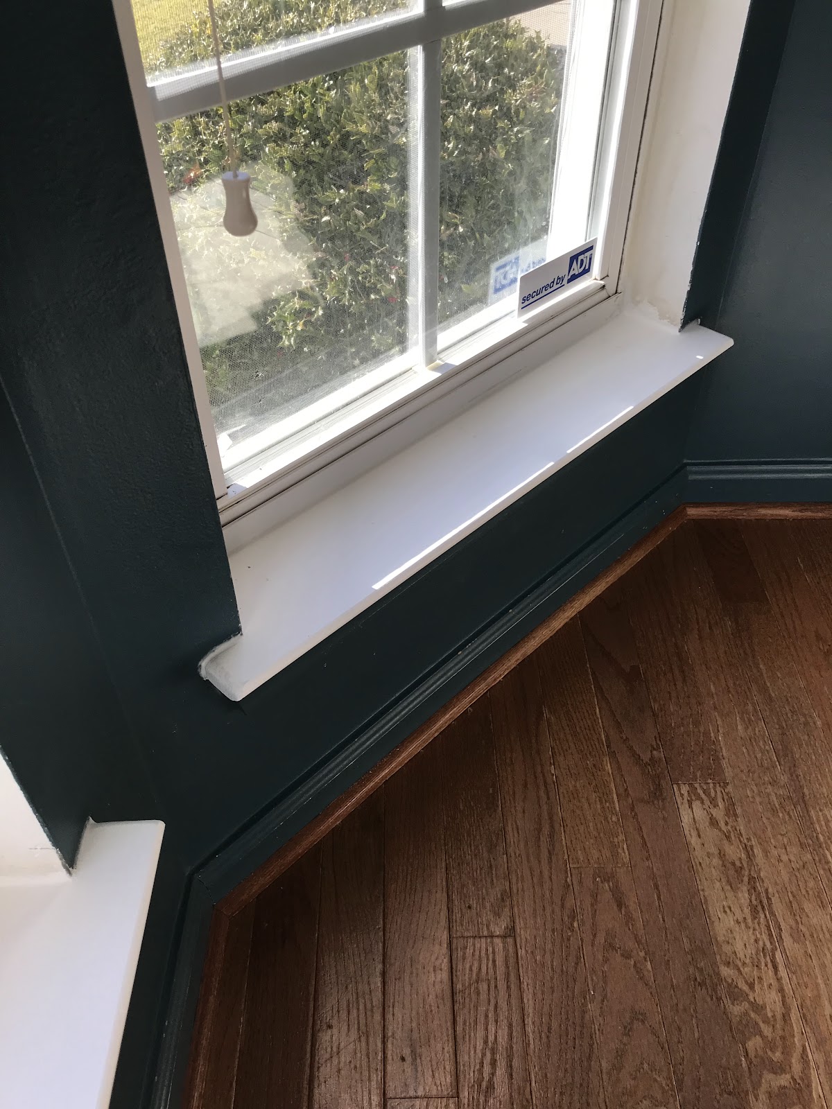 New window sill and trim against a dark green wall