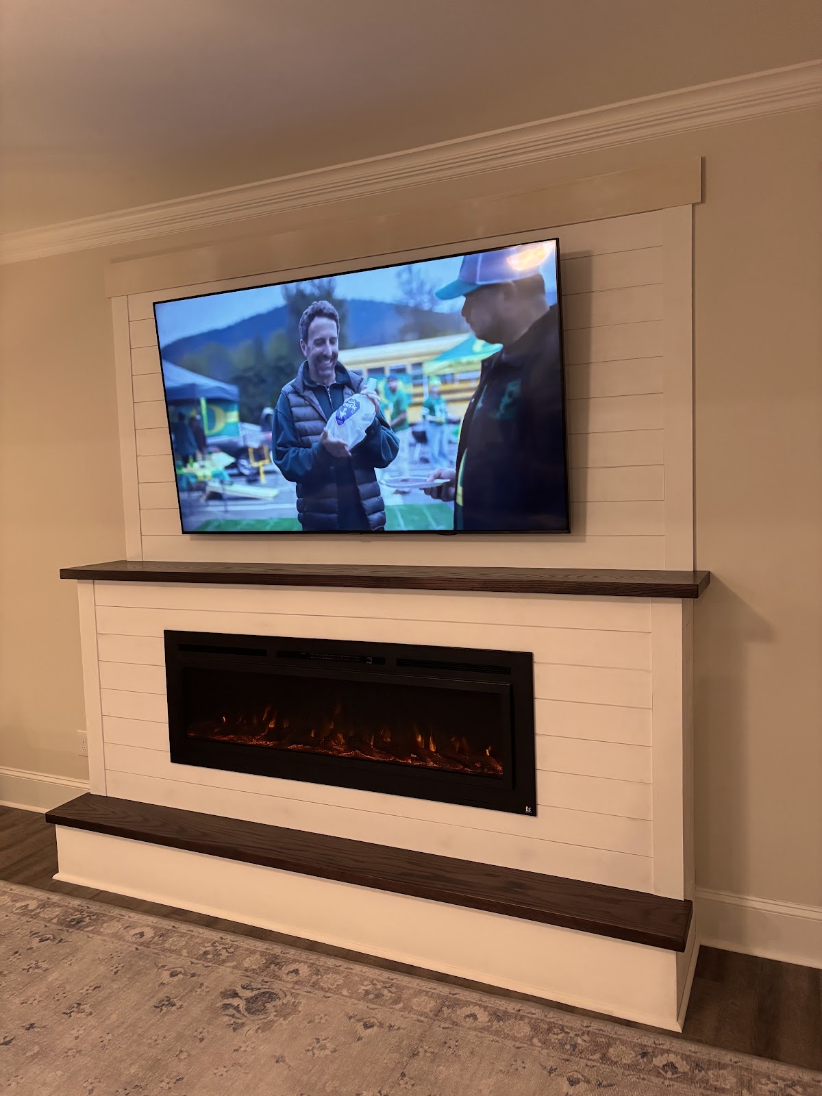 Shiplap feature wall with an electric fireplace and mounted TV built by Mill Town Handyman